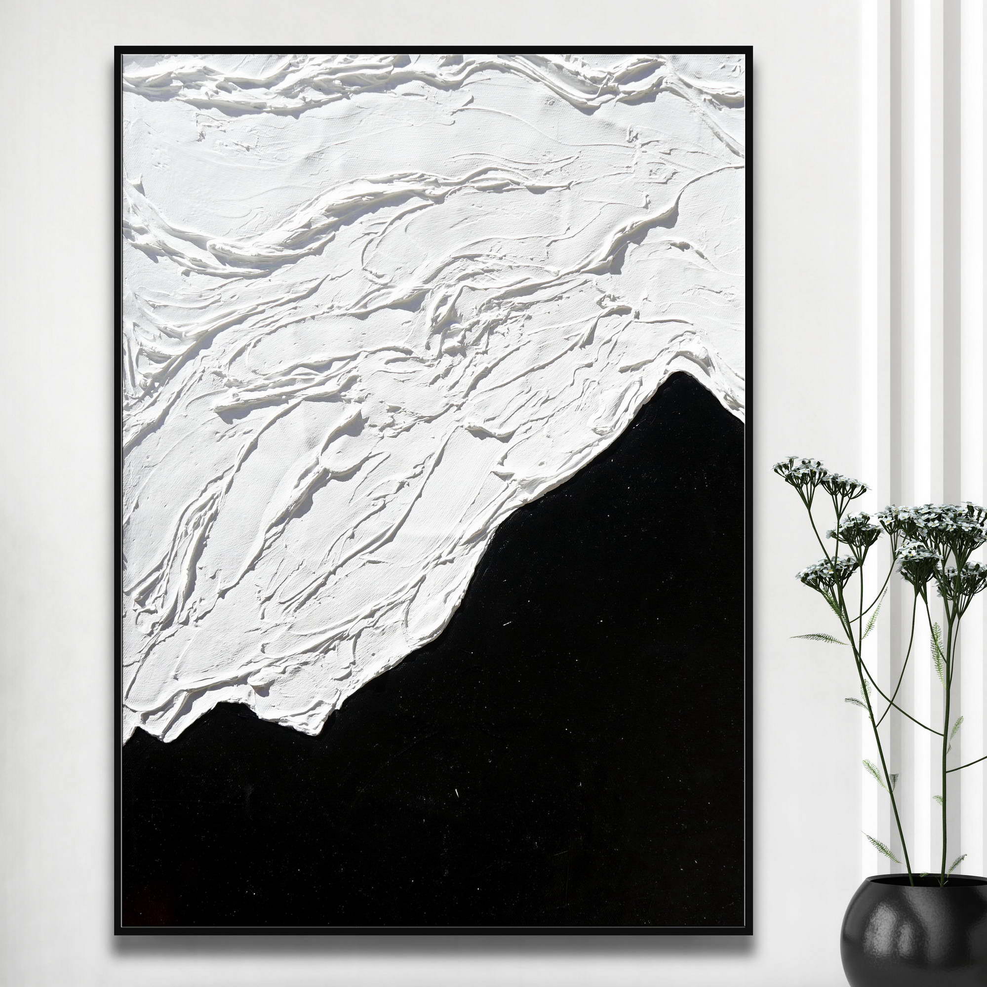 Quadro astratto con metà superiore texture bianca e metà inferiore nera liscia accanto a vaso con fiori