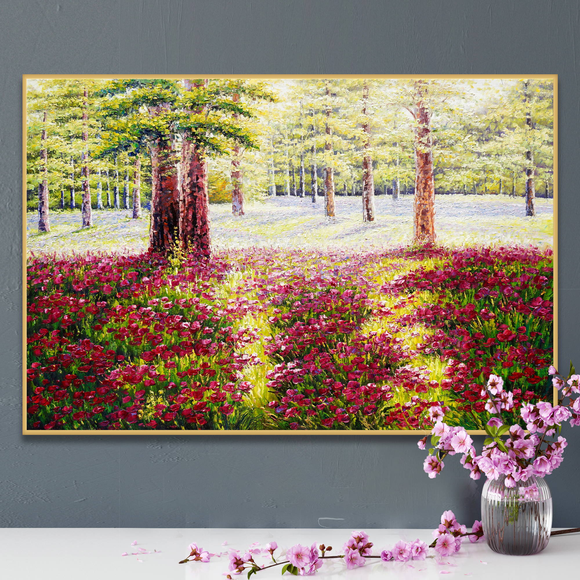 Quadro di un bosco soleggiato con fiori rossi in primo piano e alberi verdi sullo sfondo